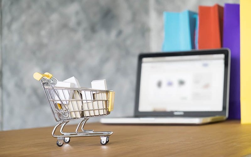 Business theme, internet online shopping concept, shopping delivery, shopping cart carry shopping mail box and blur background of shopping bag and open laptop