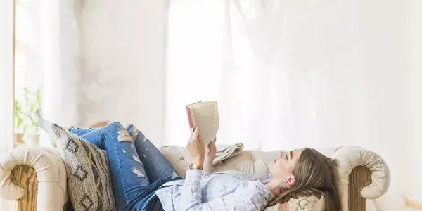 lying-woman-reading-novel-on-couch